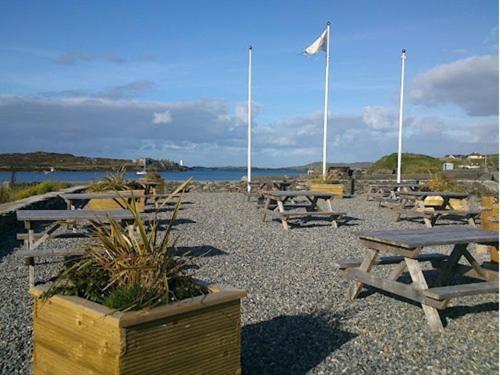 a group of picnic tables and a flag on a beach at The Beach, Days Bar and B&B in Inishbofin