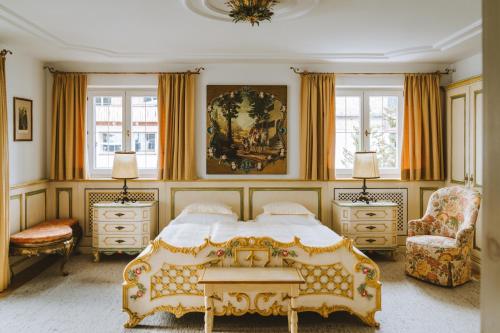 a bedroom with a bed and a chair and windows at Post Lech Arlberg in Lech am Arlberg