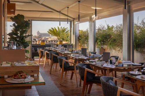 a restaurant with wooden tables and chairs and large windows at Portrait Roma - Lungarno Collection in Rome