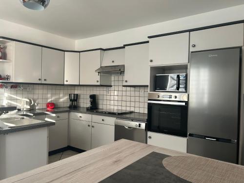 une cuisine avec des armoires blanches et un réfrigérateur en acier inoxydable dans l'établissement Chez Ana, à Ohnenheim