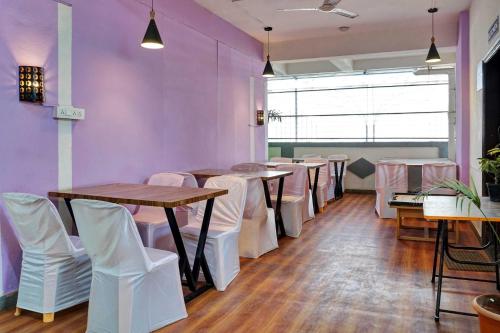 a row of tables and chairs in a room with purple walls at Super Townhouse Hinjewadi Phase 1 in Pune