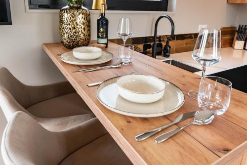 a wooden table with plates and wine glasses on it at Luxury Watervilla Near Amsterdam And Schiphol in Aalsmeer