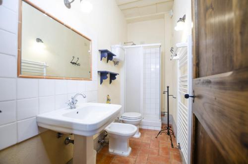 un bagno con lavandino, WC e specchio di Casale del Conte a Pienza