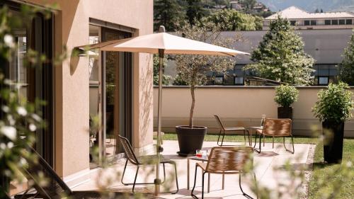 a patio with a table and chairs and an umbrella at City Hotel Merano in Merano