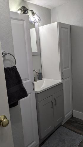 a white bathroom with a sink and a mirror at Fairbanks Great Location in Fairbanks