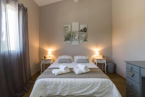 une chambre avec un grand lit avec des draps et des oreillers blancs dans l'établissement Un Coin de Provence, à LʼIsle-sur-la-Sorgue