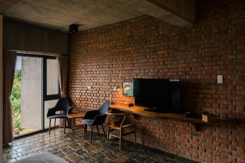 a room with a brick wall with a table and a television at The Light in Hengchun