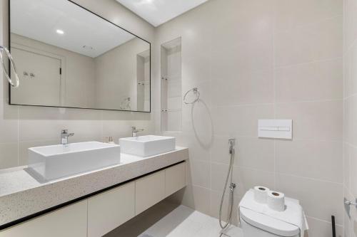 a white bathroom with a sink and a toilet at Seaside Lux Retreat 2-BR Private Beach in Dubai