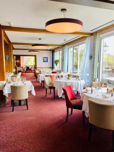 a restaurant with white tables and chairs and windows at Logis Hôtel-Restaurant Aux Trois Roses in La Petite-Pierre