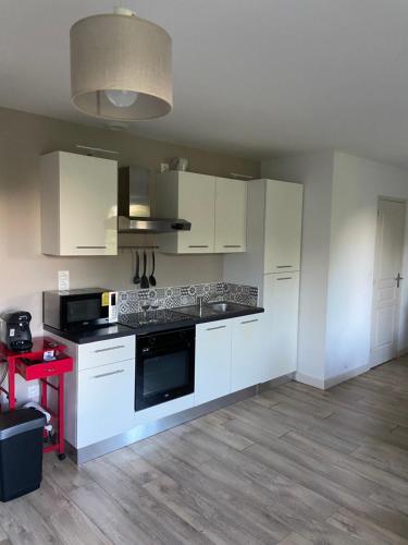 une cuisine avec des armoires blanches et un four à plaques de cuisson dans l'établissement Studio aux cœurs des remparts, à Gravelines