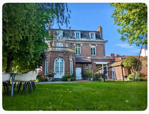 une grande maison en briques avec une table dans la cour dans l'établissement Studio aux cœurs des remparts, à Gravelines