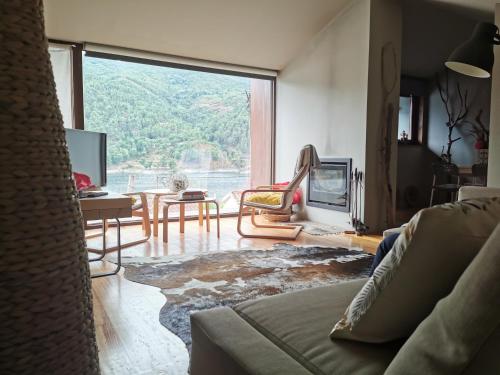 a living room with a couch and a large window at Casa do Bairro da Veiga in Pereiro