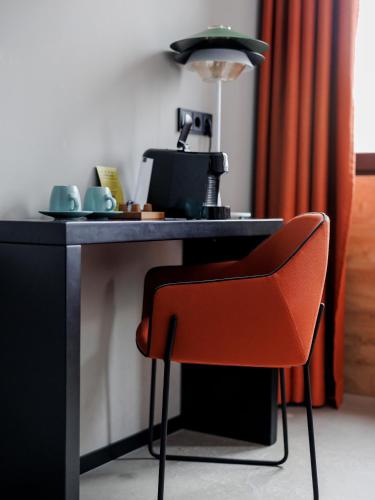 a red chair sitting at a desk with a lamp at KONCEPT HOTEL International in Cologne