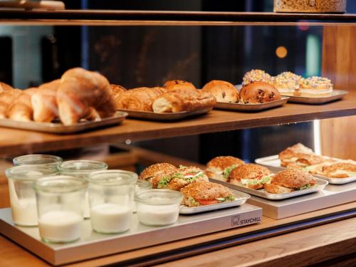a display case filled with different types of pastries and bread at KONCEPT HOTEL International in Cologne