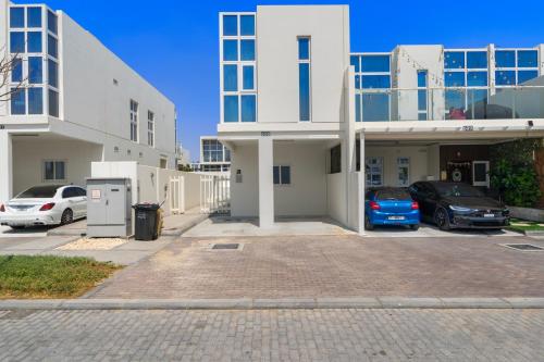 a large white building with cars parked in a parking lot at Modern 3-Bedroom Villa in Damac Hills 2 in ‘Ūd al Bayḑāʼ
