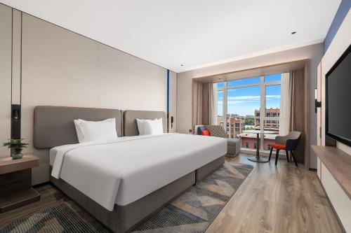 a bedroom with a large bed and a large window at Holiday Inn Express Qingdao Hongdao Station by IHG - Qingdao International Airport in Qingdao
