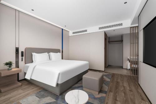 a bedroom with a white bed and a television at Holiday Inn Express Qingdao Hongdao Station by IHG - Qingdao International Airport in Qingdao