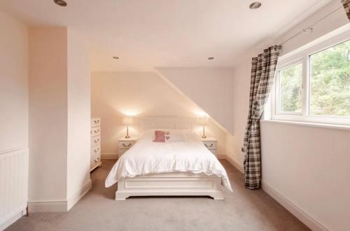 a white bedroom with a bed and a window at Riverview Cottage in Gortnessy Upper