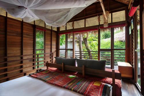 ein Schlafzimmer mit einem Bett in einem Zimmer mit Fenstern in der Unterkunft Castaway Resort Koh Lipe in Ko Lipe