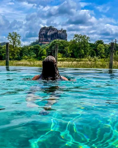 a person in the water with a rock in the background at Lankapura Heritage in Sigiriya