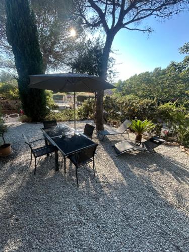 une table, des chaises et un parasol sur un champ de gravier dans l'établissement Très joli appartement Saint-Raphaël, à Saint-Raphaël