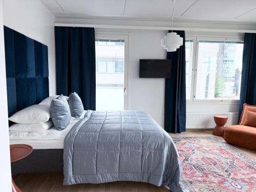 a bedroom with a bed with blue curtains at Spacious Railway Station Apartment in Oulu