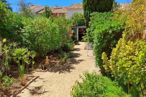 un jardin avec des buissons et des arbres et une maison dans l'établissement LES PINEDES - Un jardin fleuri à côté de la plage, au Grau-du-Roi