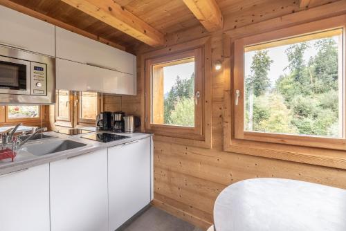 une cuisine avec des placards blancs et une grande fenêtre dans l'établissement Petit Chalet Cosy, à Combloux