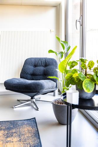 a blue chair sitting in a room with plants at London 993 Apt 202 in Antwerp