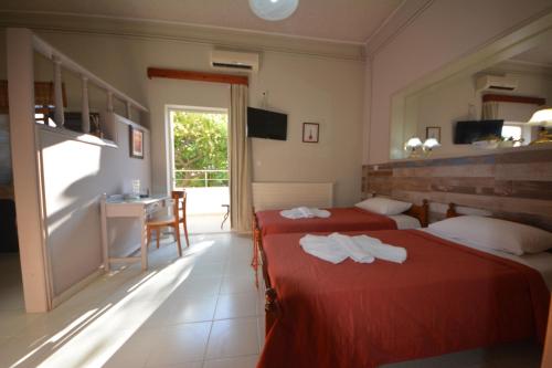 a bedroom with two beds with red sheets and a table at Bikakis Family Apartments in Kissamos