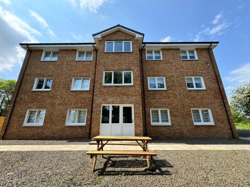 a picnic table in front of a brick building at Inchconnachan Apartment in Bonhill