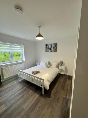 a bedroom with a white bed and a window at Inchconnachan Apartment in Bonhill