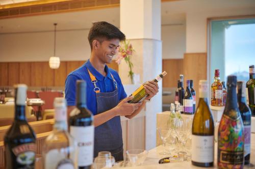 a man in an apron holding a bottle of wine at The Dukes Retreat Khandala in Lonavala