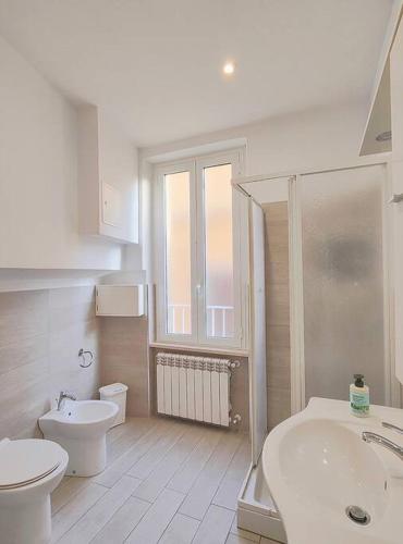 a white bathroom with a toilet and a sink at La Vie est Belle in Nettuno