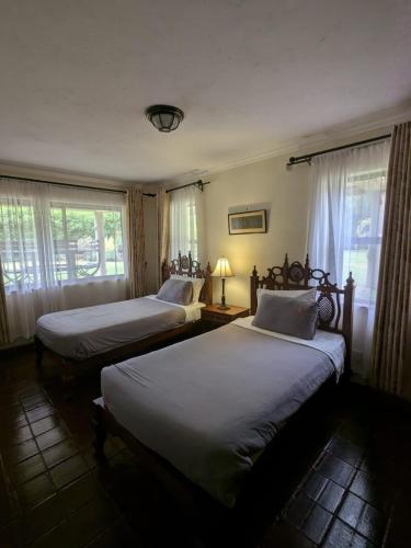 two beds in a room with two windows at Kwezi Cottage at The Great Rift Valley Lodge & Golf Resort Naivasha in Naivasha