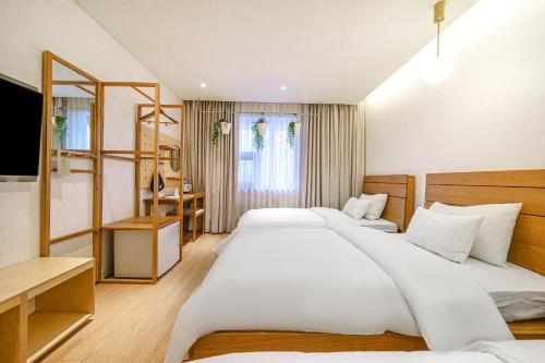 a hotel room with two beds and a desk at Chuncheon Hey Hotel in Chuncheon