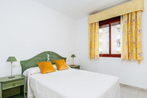 sypialnia z łóżkiem z pomarańczowymi poduszkami i oknem w obiekcie Apartamentos Topacio Unitursa w mieście Calpe