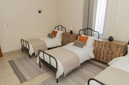 two beds in a room with white walls at Wateera Jebel Sifah in As Sīfah