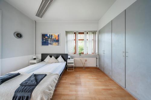 a white bedroom with a large bed and a desk at Bergblick Apartments in Innsbruck