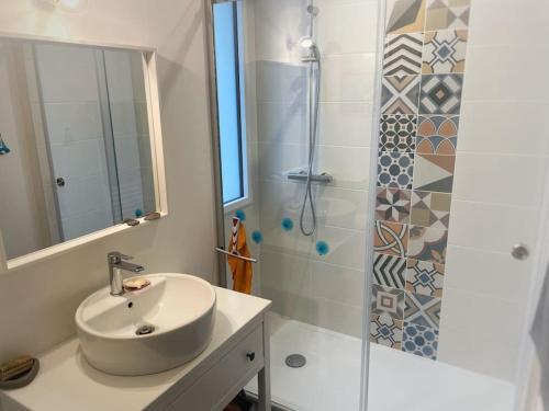 une salle de bain blanche avec un lavabo et une douche dans l'établissement Villa cosy à deux pas de la plage - Classée 3 étoiles, à Les Sables-dʼOlonne