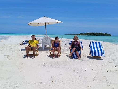 three people sitting on the beach under an umbrella at Rindali - The speedboat from Malé to the hotel departs at 1130 every Monday Thursday and Saturday and from the hotel to Malé at 0630 and five domestic flights are available every day in Dhaalu Atoll