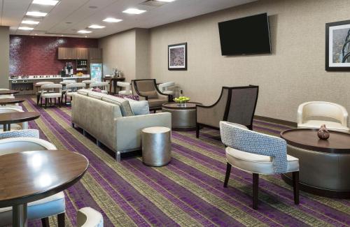 a waiting room with tables and chairs and a tv at Hilton Washington DC/Rockville Hotel & Executive Meeting Center in Rockville