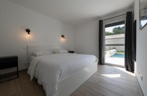 une chambre blanche avec un lit et une grande fenêtre dans l'établissement Villa 4 chbres avec piscine (10), à Saint-Augustin