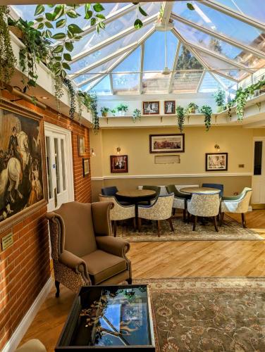 a conservatory with chairs and tables and a glass ceiling at Chevrons Living in Fordingbridge