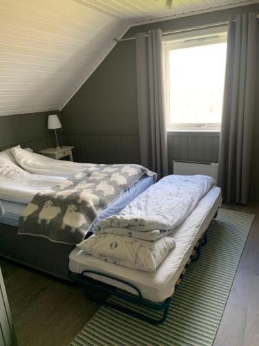 a bedroom with two beds and a window at Villa med sauna ute, egen båt, naust og kai in Breidvik