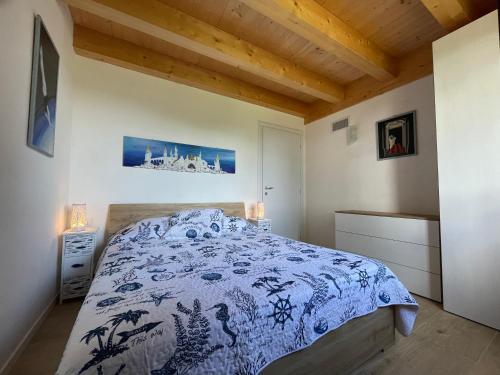 a bedroom with a bed with a blue and white comforter at La casetta di marzapane casa-natura in Senigallia