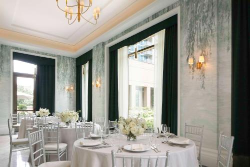 a dining room with white tables and chairs and a chandelier at Waldorf Astoria Atlanta Buckhead in Atlanta