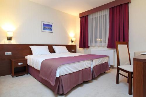 una camera d'albergo con un grande letto con tende rosse di Hotel Arena Expo a Danzica