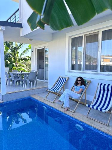 a woman sitting in chairs next to a swimming pool at Lavender Villas in Dalaman