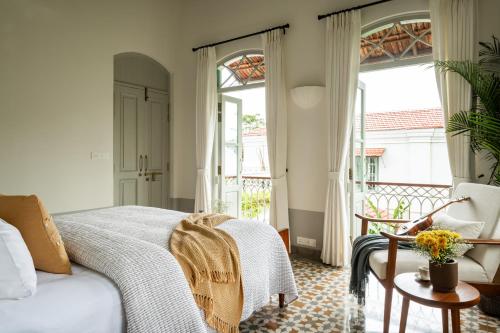 a bedroom with a bed and a balcony with windows at La Rozalia, Exquisite 4 BHK Villas with Large Pool, Garden, Dedicated Caretaker, Terrace, 2 mins from the famous Dear Zindagi Road in Mapusa